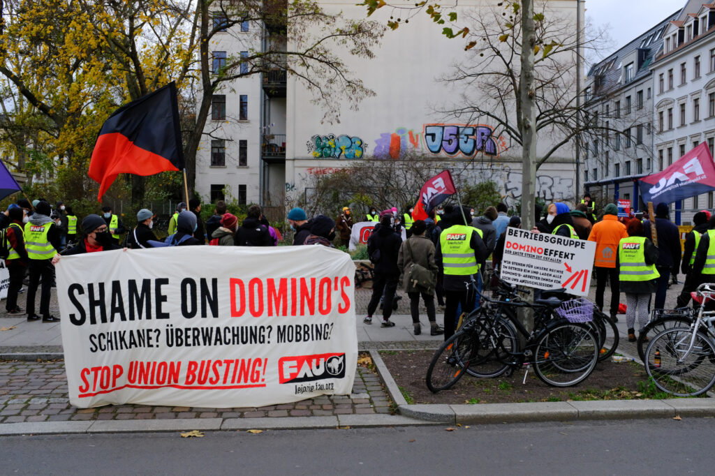 Viele Leute mit Bannern in der Nähe des Domino's Store Leipzig-Süd